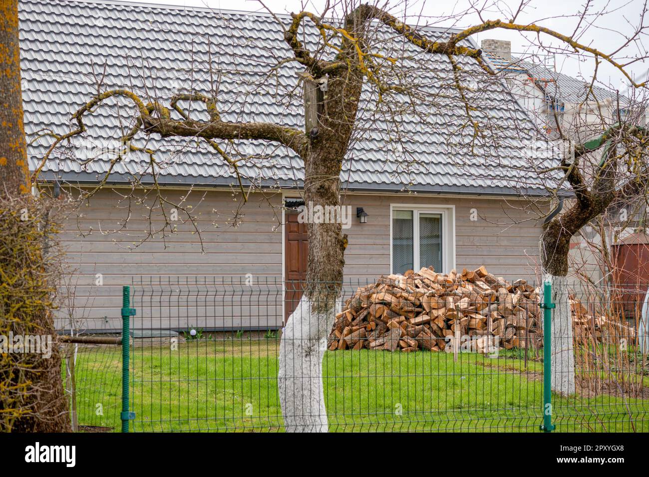 Ein Haus mit einem Zaun und einem Haufen Brennholz dahinter. Stockfoto
