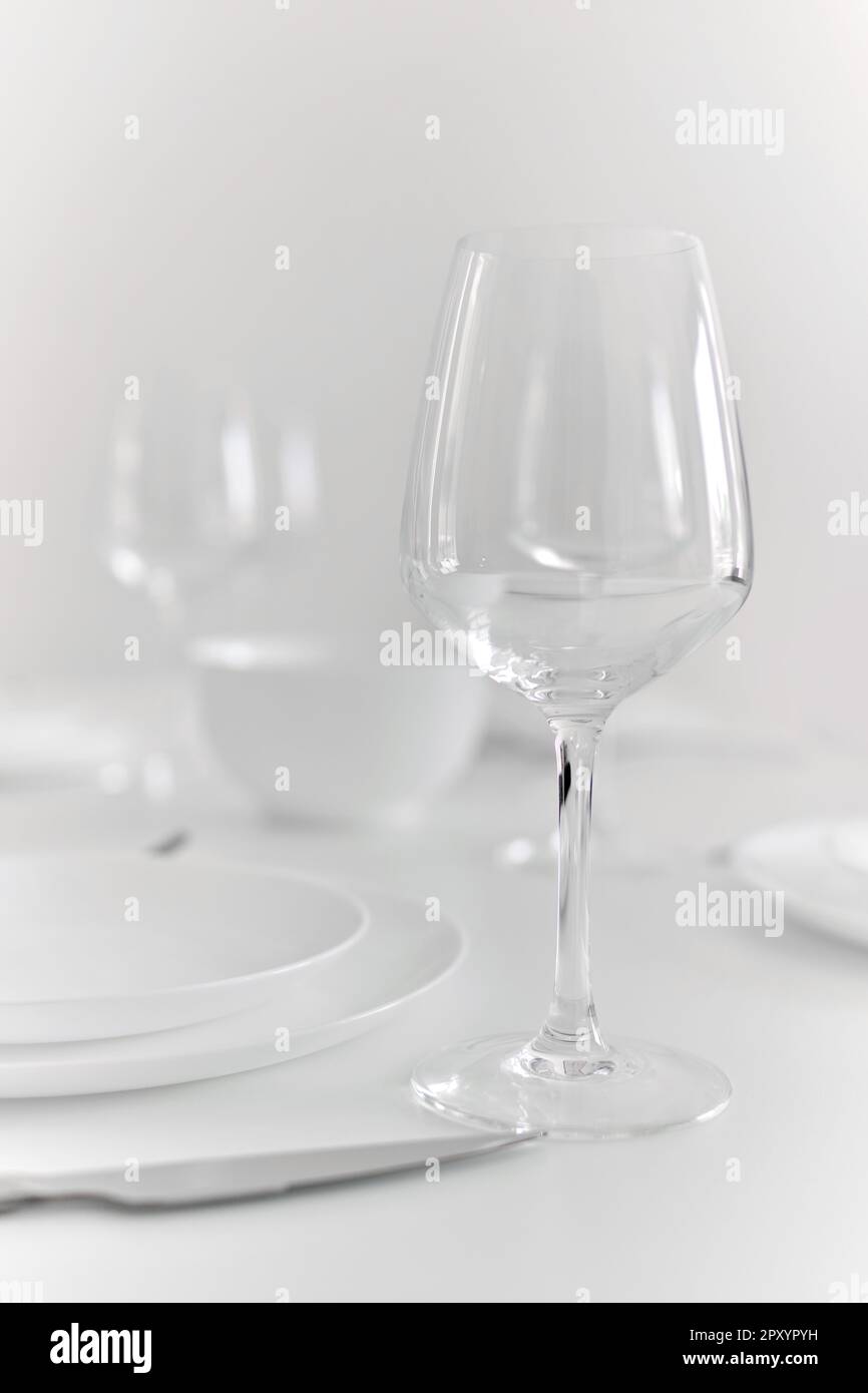 Nahaufnahme eines leeren Weinglases auf dem Tisch, zubereitet zum Abendessen mit Tischdecken und Tellern, keine Menschen. Essen, Lebensereignis-Feier Stockfoto