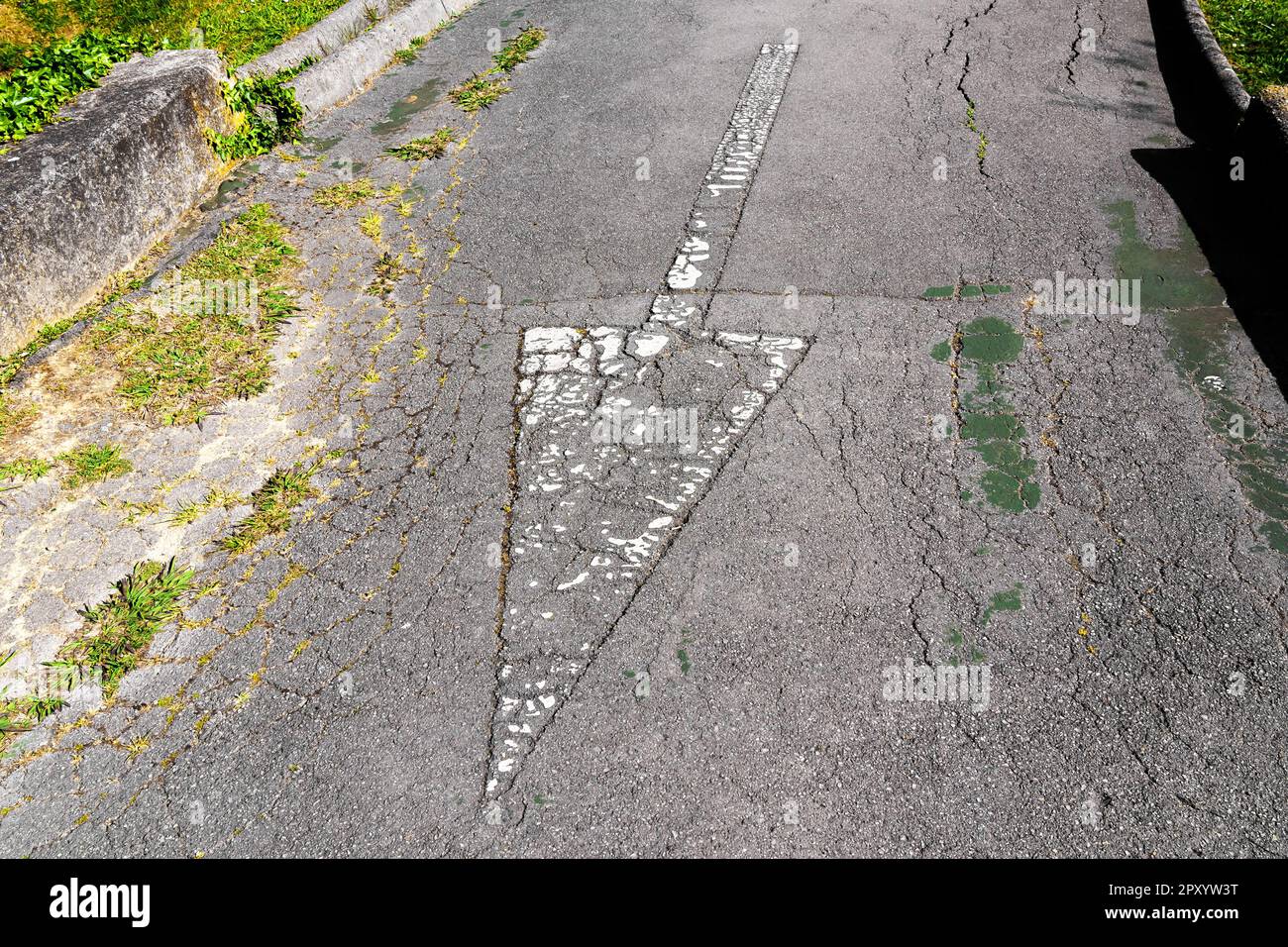 Pfeil in Rückwärtsrichtung auf einer verwitterten Asphaltstraße, Nahaufnahme Stockfoto