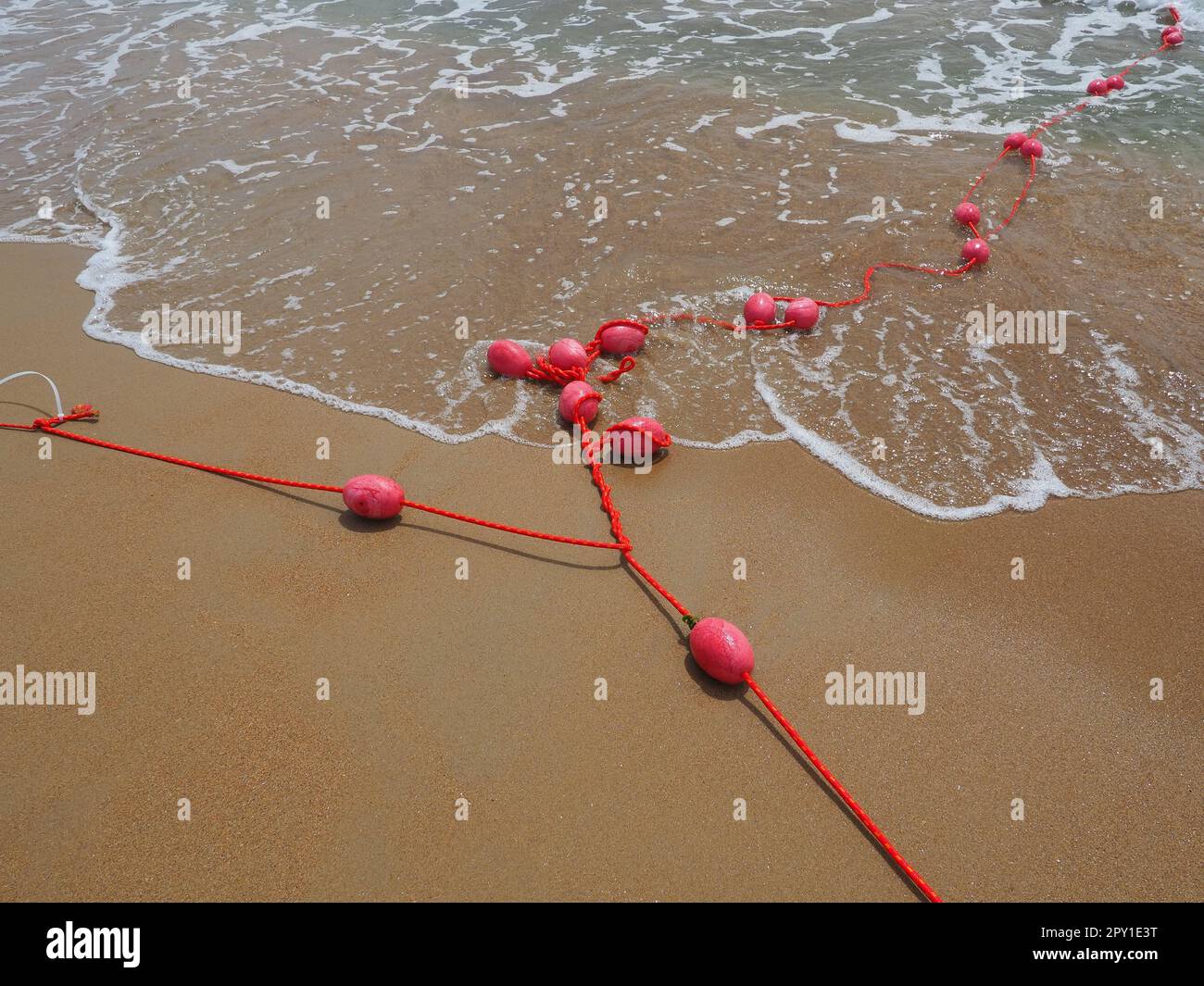 Bojen an einem Seil im Meerwasser. Die Rettungsringe sind rosa gefesselt, um die Leute auf die Wassertiefe aufmerksam zu machen. Rettung des Ertrinkens. Einen Ort abgrenzen Stockfoto