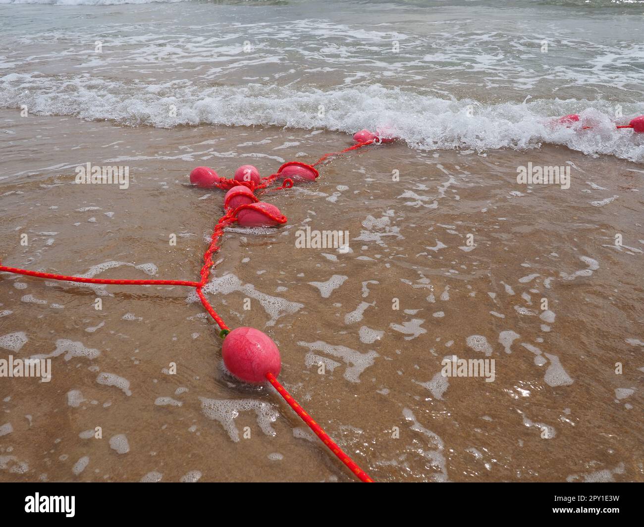 Bojen an einem Seil in der Nähe von Meerwasser. Die Rettungsringe sind rosa gefesselt, um die Leute auf die Wassertiefe aufmerksam zu machen. Rettung des Ertrinkens. Begrenzen einer Sperre Stockfoto