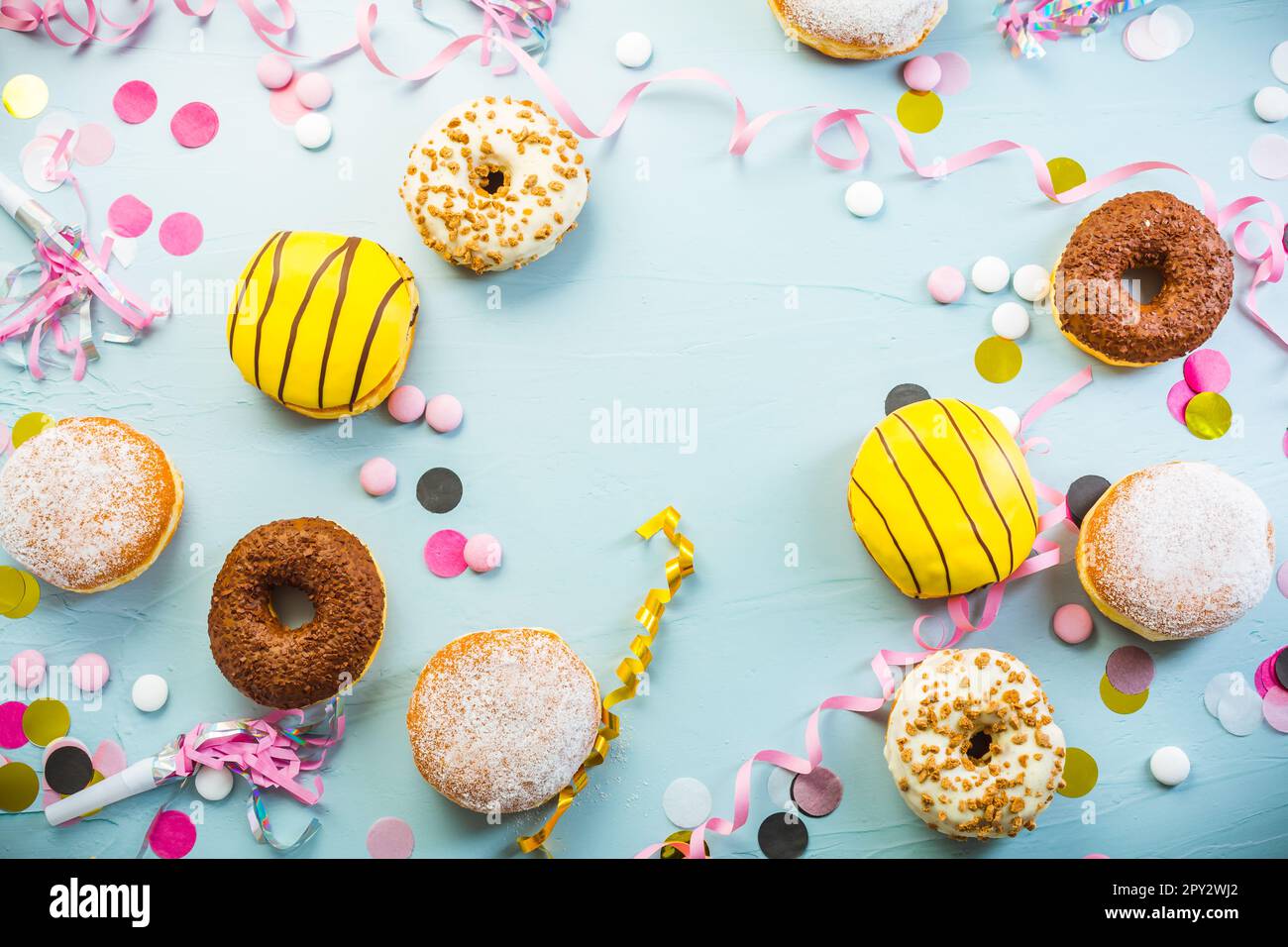 Deutsche Krapfen oder Donuts mit Bändern und Konfetti. Traditioneller Berliner für Karneval und Party. Farbenfrohes Karneval- oder Geburtstagsbild Stockfoto