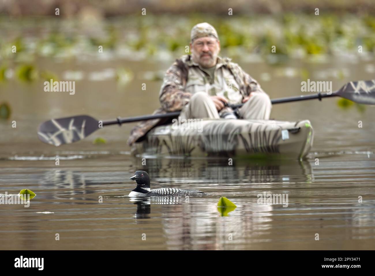 Ein Editorial-Foto eines Fotografen in einem Kajak, der auf dem Fernan Lake in Nord-Idaho einen Wasserflugzeug fliegt. Stockfoto