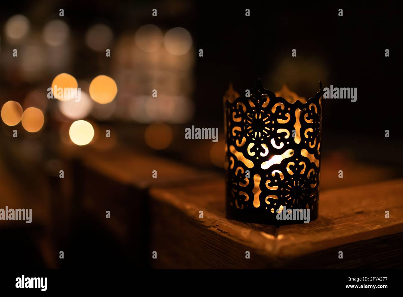 Beleuchtete Kerze am Tischrand mit unscharfem Hintergrund Stockfoto