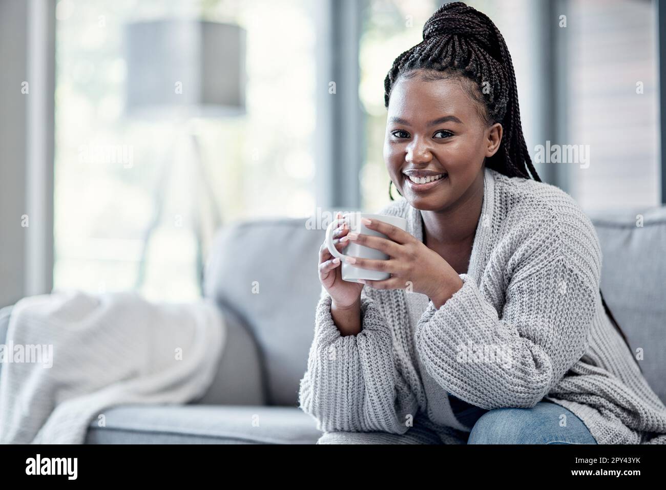 Nichts kommt dem Komfort des eigenen Zuhauses näher. Eine junge Frau, die zu Hause eine entspannende Kaffeepause auf dem Sofa macht. Stockfoto