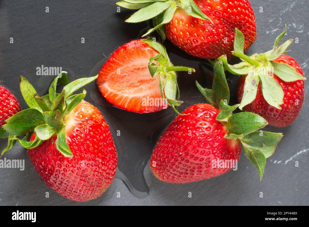 Sechs frische rote Erdbeeren mit Wasser auf neutralem Hintergrund Stockfoto