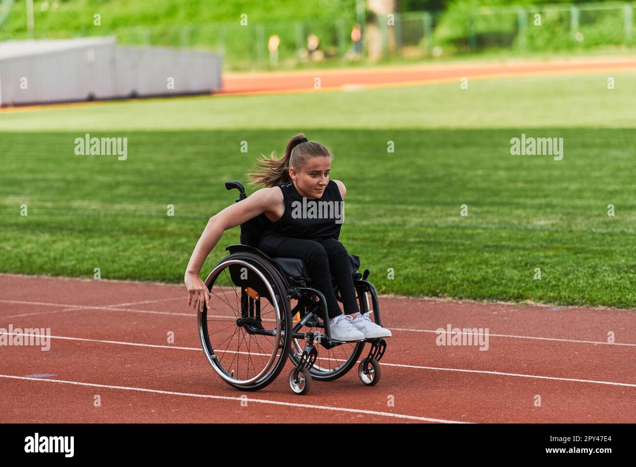 Eine behinderte Frau, die einen Rollstuhl auf einer Rennstrecke fährt, während sie sich auf die Paralympischen Spiele vorbereitet Stockfoto