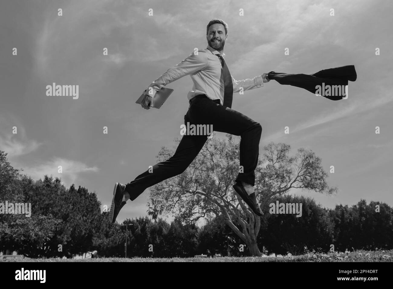 Geschäftsmann im Anzug, der über den Stadtpark springt. Schnelles Geschäftskonzept. Stockfoto
