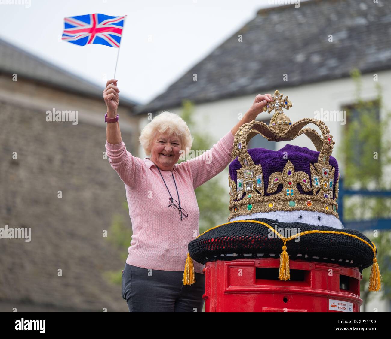 Selkirk, Großbritannien. 02. Mai 2023. 2. Mai 2023 das King-Charles-Krönungsfieber hat die schottische Grenzstadt Selkirk mit bunten gestrickten Hängekörben und einer wunderbaren riesigen Strickkrone oben auf dem roten Briefkasten der Stadt getroffen. Die Bombenangriffsgruppe von Souter Stormers ist für die bunten Szenen verantwortlich. Daphne Pratt, ein Team hinter dem extravaganten Strickstil, hat eine fantastische goldene Strickkrone geschaffen, die auf dem Hauptpostkasten der Stadt platziert wurde. Kredit: phil wilkinson/Alamy Live News Stockfoto