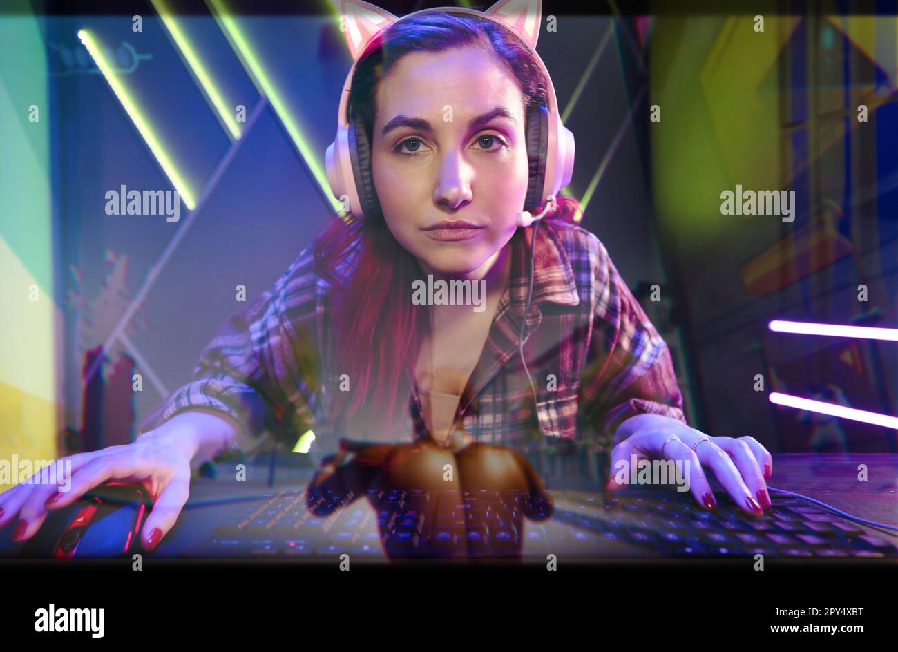 Weibliche Gamer, die sich auf ihren Computerbildschirm konzentriert, während sie ein Ego-Shooter-Videospiel in hoher Auflösung navigiert. Eine Frau, die eine intensive und enga hat Stockfoto