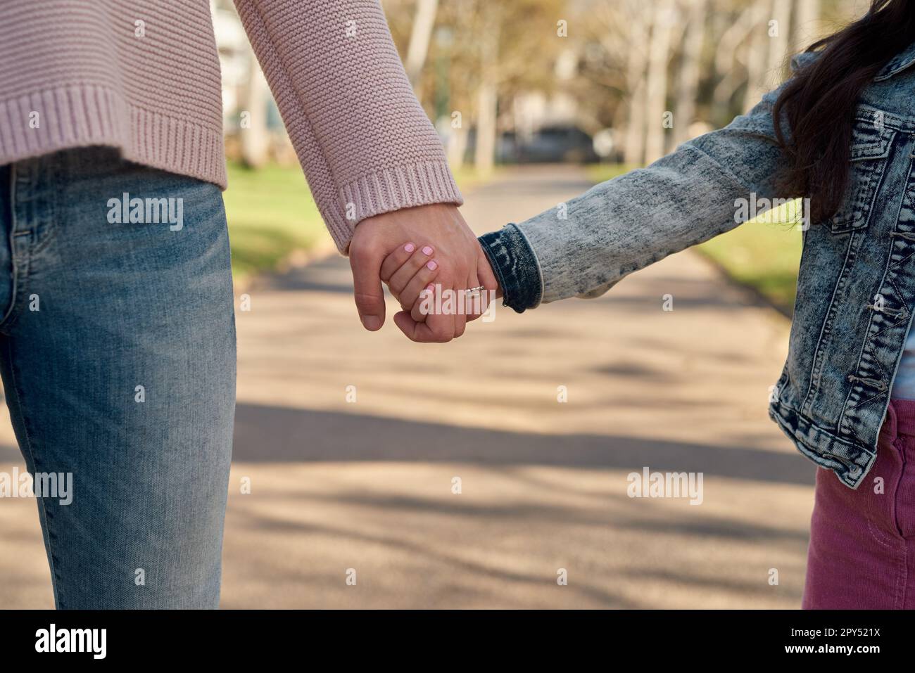 Nur ich und meine Mama. Ein kleines Mädchen, das die Hand seiner Mutter hält, während es einen Spaziergang im Park macht. Stockfoto