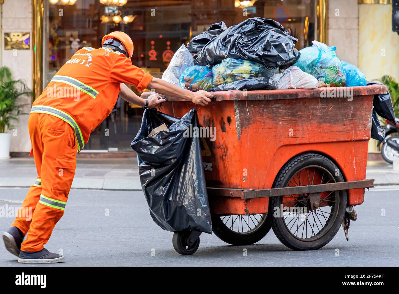 Müllsammler in Warnkleidung mit Transportwagen auf Straßen in Ho-Chi-Minh-Stadt, Vietnam Stockfoto