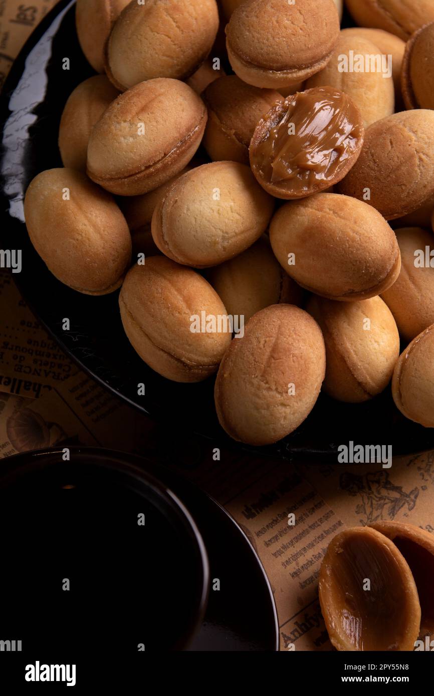 Foto eines hausgemachten Desserts mit Kondensmilch auf einem Teller und zwei Kaffeetassen Stockfoto