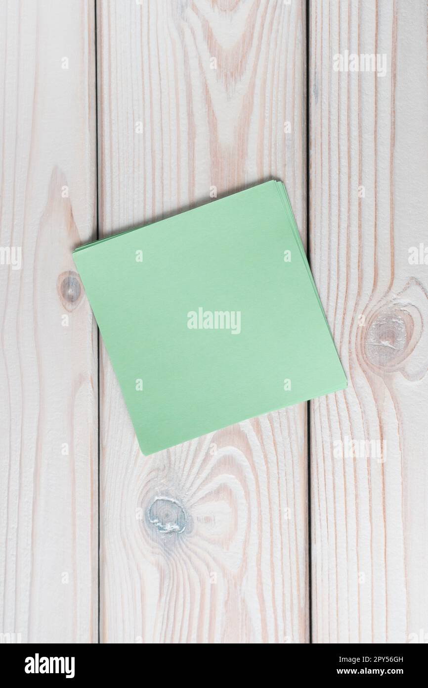 Flache Verlegung eines leeren grünen Aufklebers auf einem grauen Holztisch. Notiz, Papier, Erinnerung, Information, Gedächtnis. Stockfoto