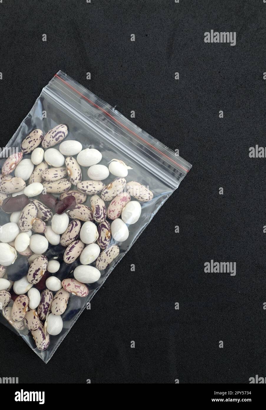 Nahaufnahme der Bohnensamen in der Packung, Packung voll mit Bohnensamen auf schwarzem Hintergrund Stockfoto