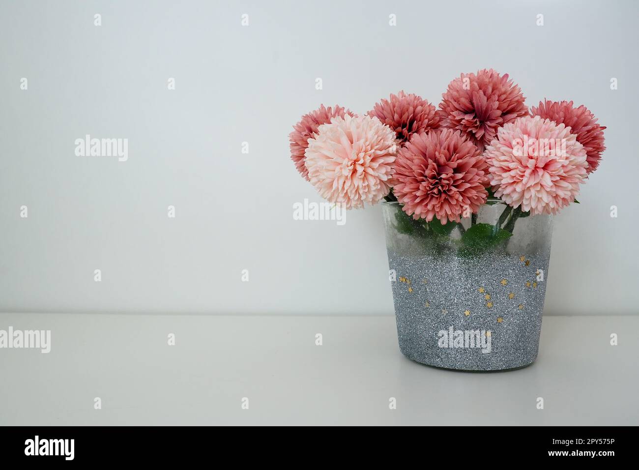 Strauß aus rosafarbenen künstlichen Frottblumen in einer grauen silbernen Vase auf weißem Hintergrund. Stillleben, Dekoration möglich. Zimmereinrichtung. Geben Sie Platz für Text frei. Stockfoto