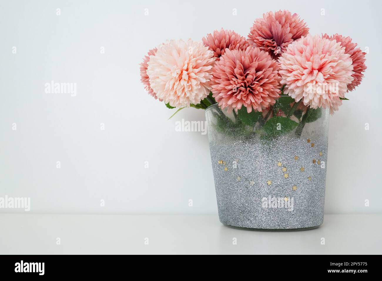 Strauß aus rosafarbenen künstlichen Frottblumen in einer grauen silbernen Vase auf weißem Hintergrund. Stillleben, Dekoration möglich. Zimmereinrichtung. Geben Sie Platz für Text frei. Stockfoto