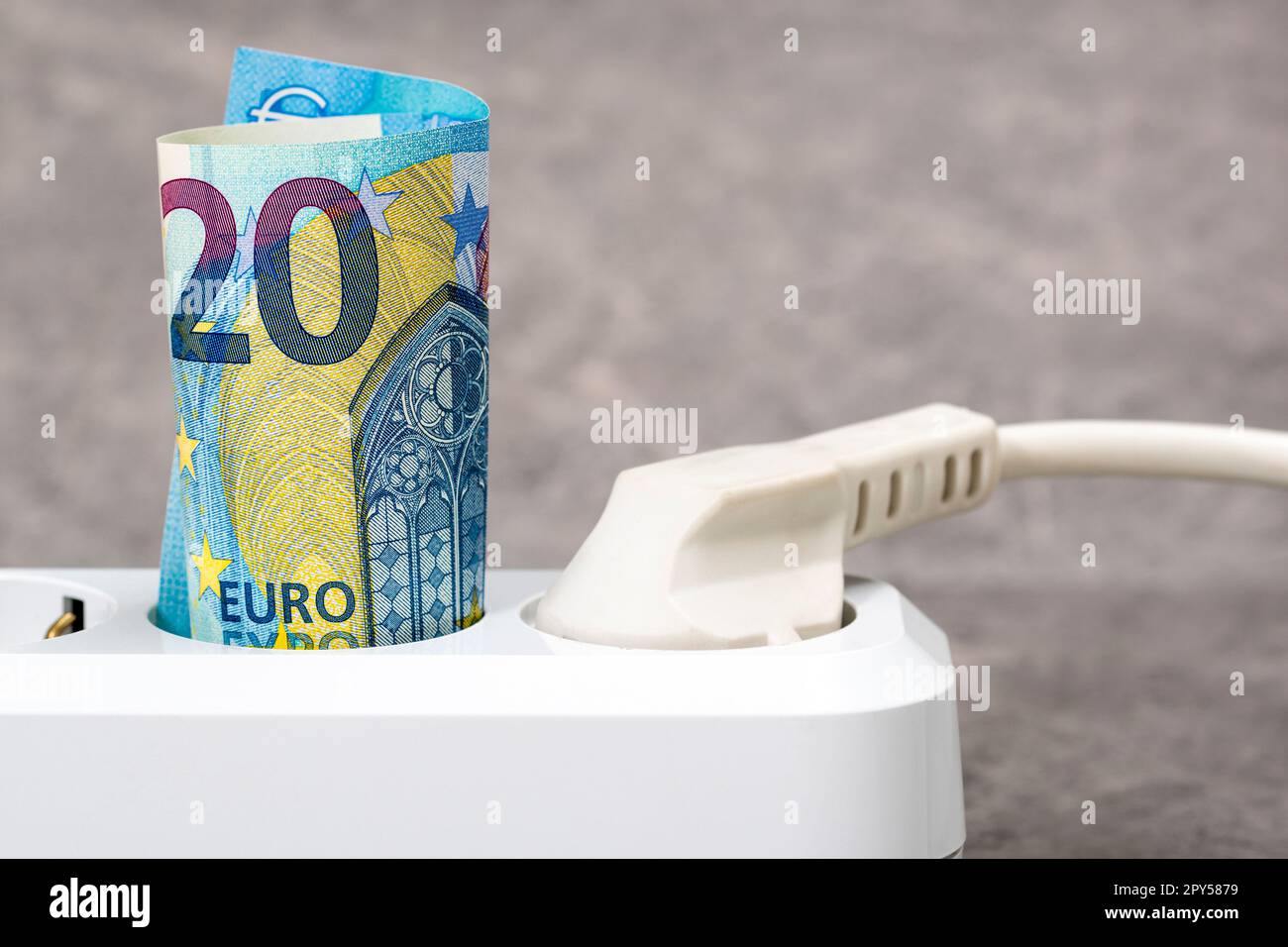 Zwanzig Euro-Banknoten, die in eine weiße Steckdosenleiste gesteckt werden Stockfoto