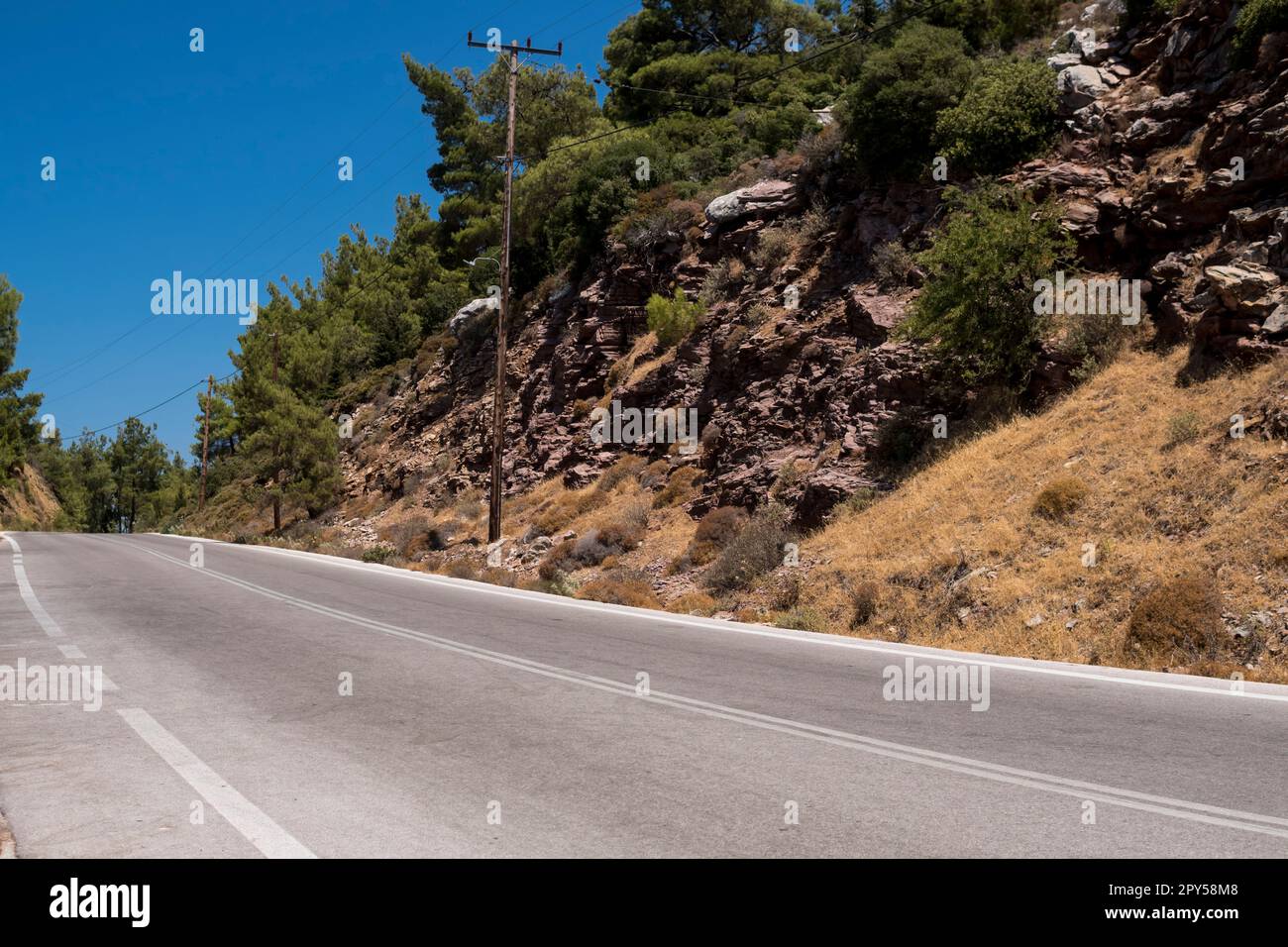 Asphaltstraße vor den Bergen an sonnigen Tagen in Griechenland Stockfoto