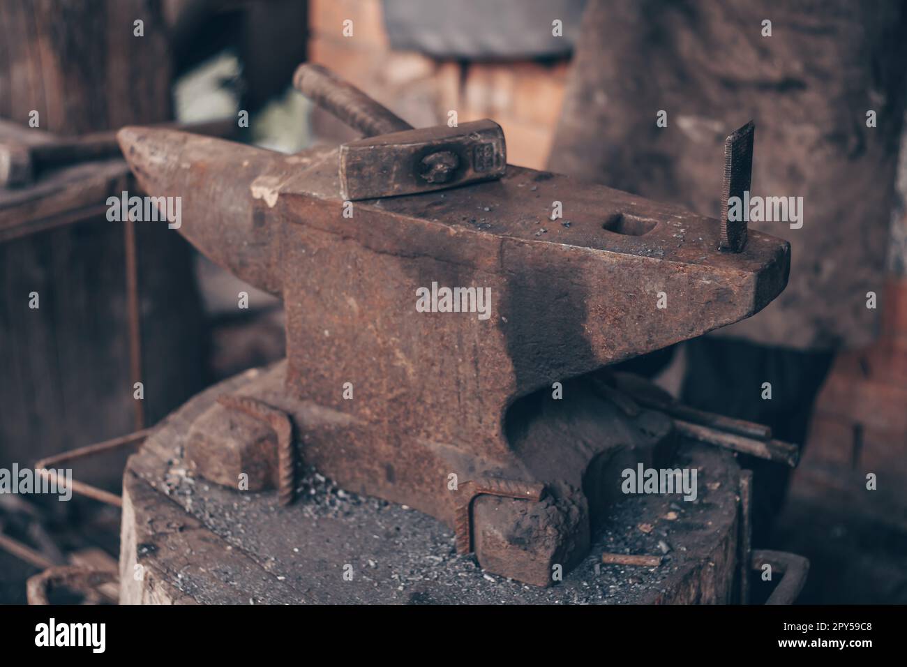 Bearbeiten Sie Metall mit einem Hammer auf Amboss in Schmiede. Schlagen Sie das Eisen im Freien in der Werkstatt an. Metallarbeiten, Schmieden. Stockfoto