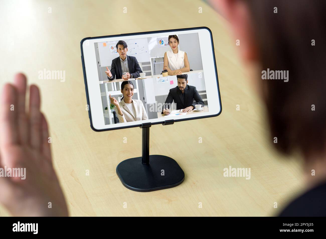 Rückansicht eines Geschäftsmanns, der am Schreibtisch im Büro sitzt und auf den Tablet-PC-Monitor schaut, während er eine Online-Videokonferenz mit einem Geschäftspartner abhält. Stockfoto