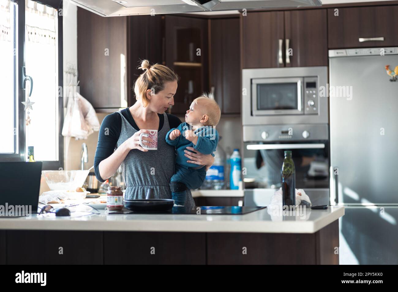 Glückliche Mutter und kleiner kleiner Junge, die zusammen Pfannkuchen zum Frühstück in der Hausküche machen. Familie, Lebensstil, häusliches Leben, Essen, gesunde Ernährung und Menschen Konzept. Stockfoto