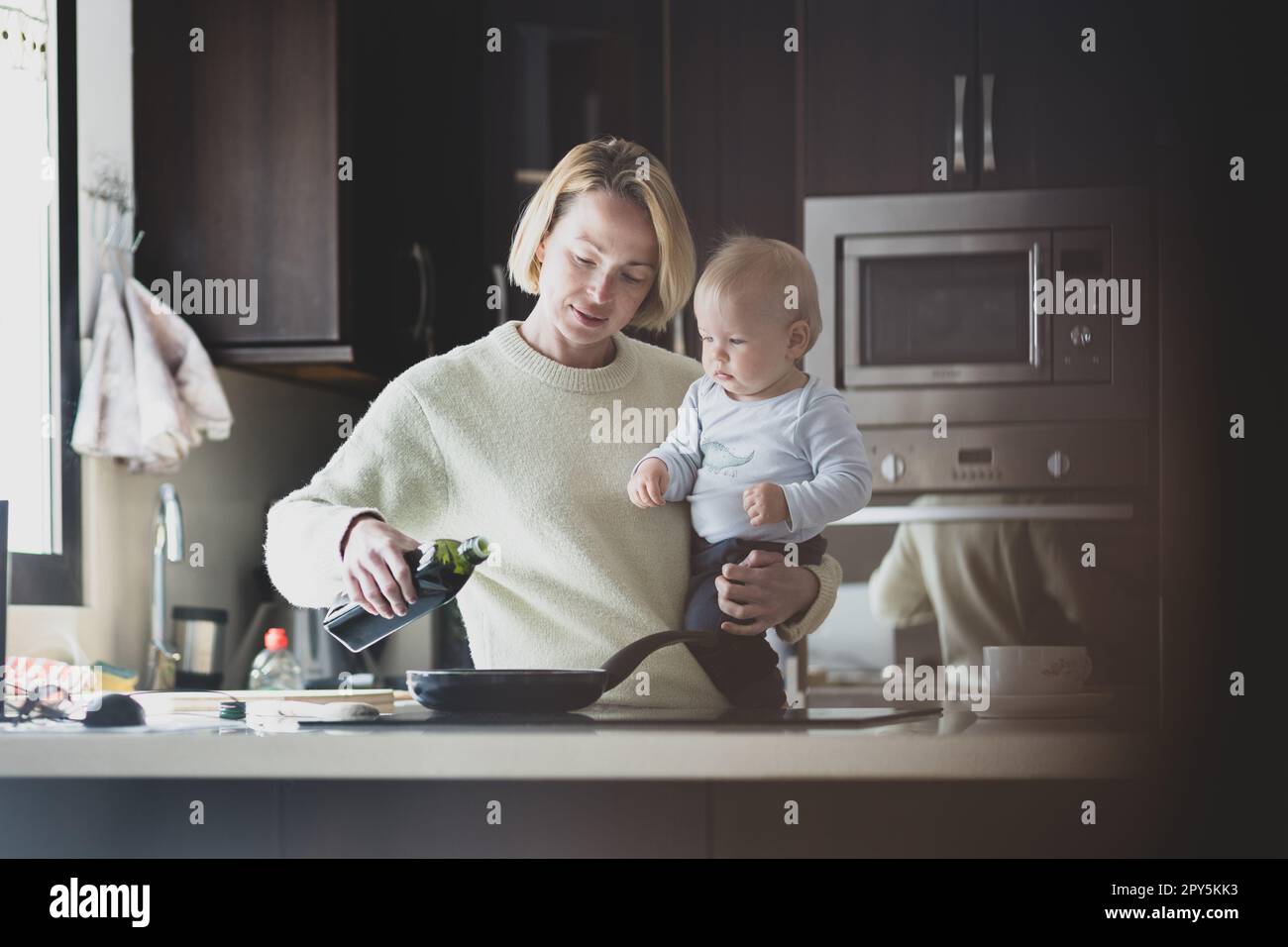 Glückliche Mutter und kleiner kleiner Junge, die zusammen Pfannkuchen zum Frühstück in der Hausküche machen. Familie, Lebensstil, häusliches Leben, Essen, gesunde Ernährung und Menschen Konzept. Stockfoto