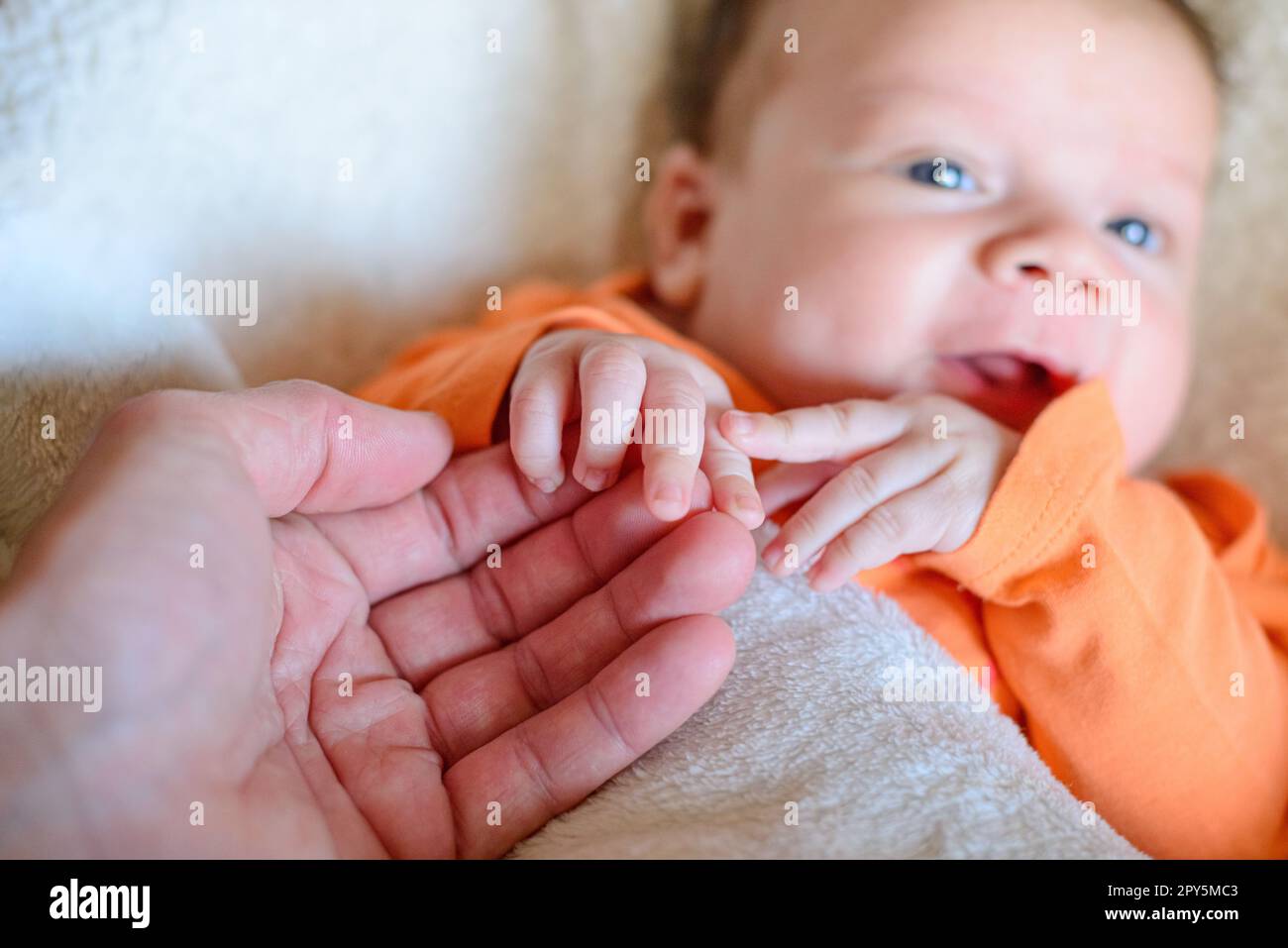 Süßes, neugeborenes, weißes Baby, das die Hand seiner Mutter hält Stockfoto