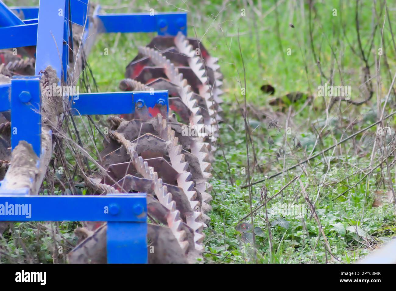 Blaue schwere landwirtschaftliche Geräte wie Pflug mit scharfen Stahlscheiben für den landwirtschaftlichen Ackerbau mit traktorgezogenen Geräten zur Vorbereitung der Feldarbeit erleichtern die Mechanisierung harter Landwirtschaftsarbeiten Stockfoto