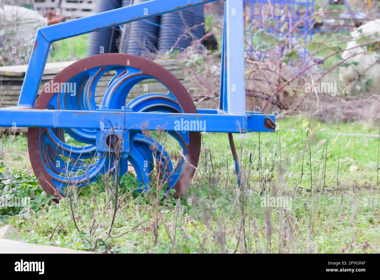Blaue schwere landwirtschaftliche Geräte wie Pflug mit scharfen Stahlscheiben für den landwirtschaftlichen Ackerbau mit traktorgezogenen Geräten zur Vorbereitung der Feldarbeit erleichtern die Mechanisierung harter Landwirtschaftsarbeiten Stockfoto