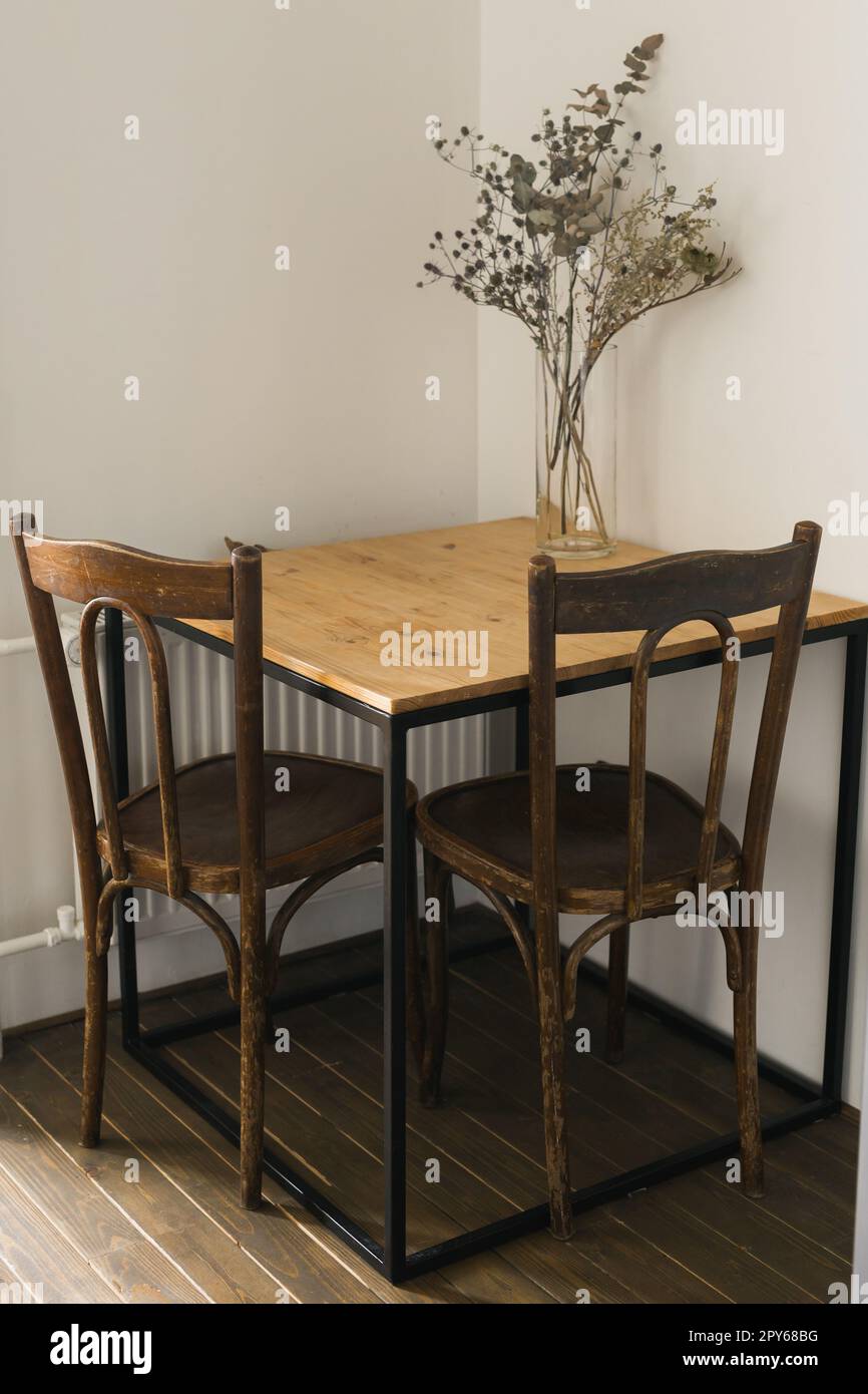 Trockene Pflanzen im minimalistischen Glasgefäß. Vertikales Bild eines Astes mit trockenen Blättern in einer eleganten, einfachen Glasvase. Dekoration und Innendesign Stockfoto