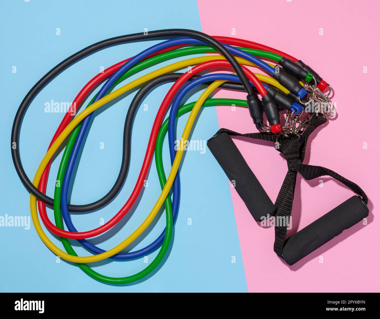 Gummi-Sportsimulator-Expander auf blaurosa Hintergrund, Draufsicht Stockfoto