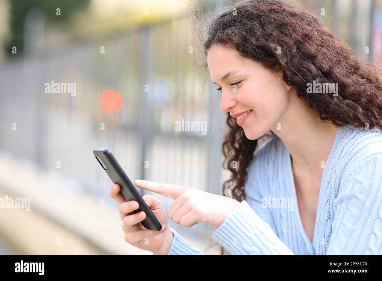 Glückliche Frau überprüft Smartphone auf der Straße Stockfoto