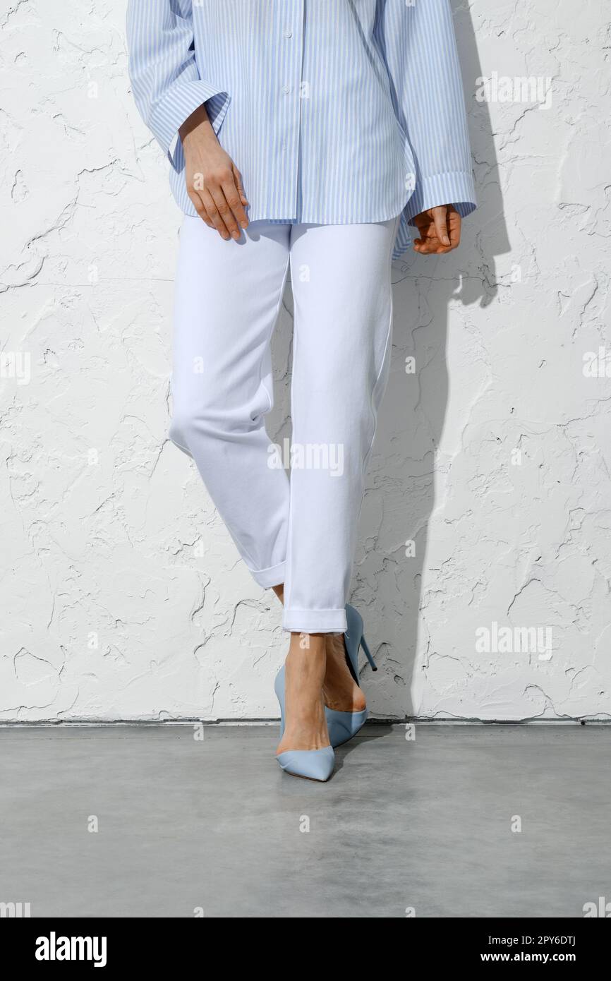 Weibliche Beine in weißen Jeans, blauem Hemd und Schuhen mit hohem Absatz Stockfoto