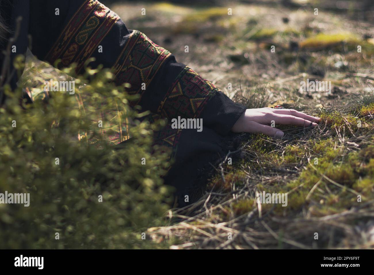Nahaufnahme weiblicher Hand in ethnischer Kleidung beim Berühren von Gras Konzeptfoto Stockfoto