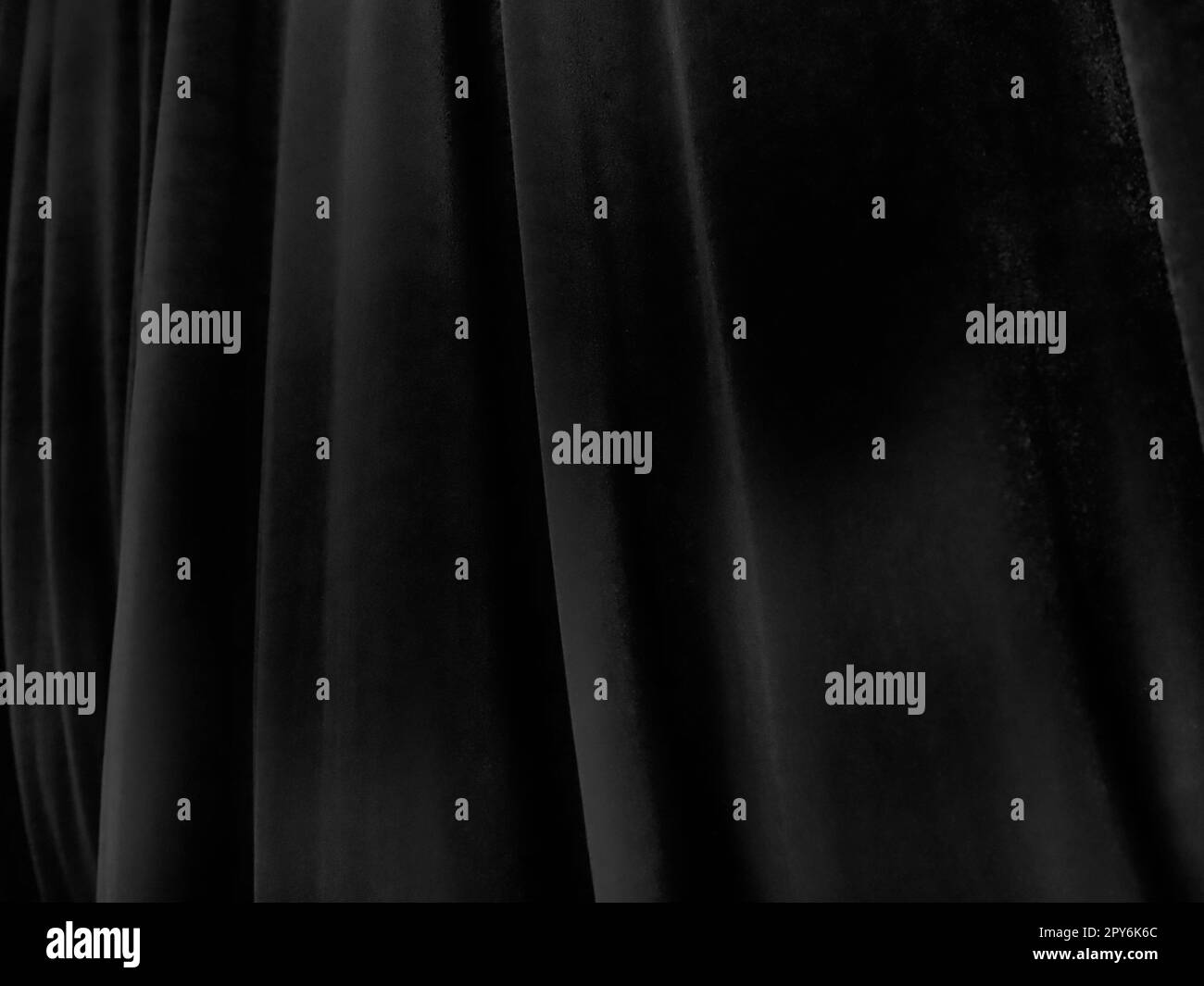 Weiche Wellen auf schwarzen Samtvorhängen. Stilisiertes Unschärfe-Bild. Dunkle Vorhänge aus angenehmem Stoff. Falten an den Vorhängen. Abstrakter schwarzer und grauer Hintergrund. Stockfoto