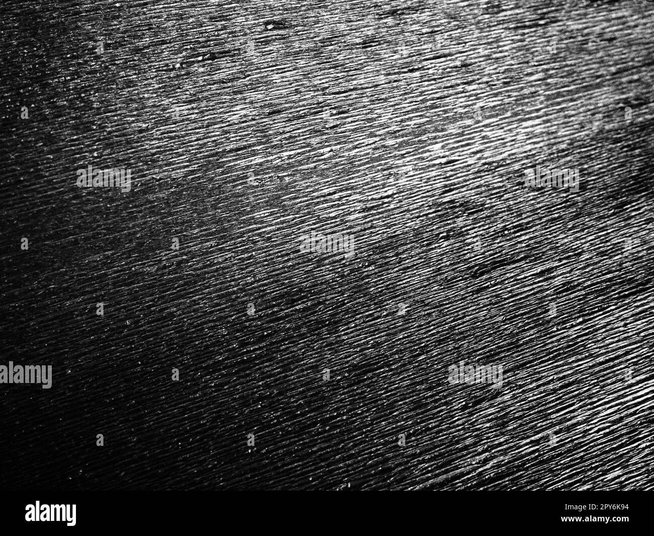 Schwarzes oder graues Wellpapier. Unebene Oberfläche. Abstrakter einfarbiger Hintergrund. Gewellte Kanten des Papierbogens. Lichtverlauf. Gewellte Textur Stockfoto