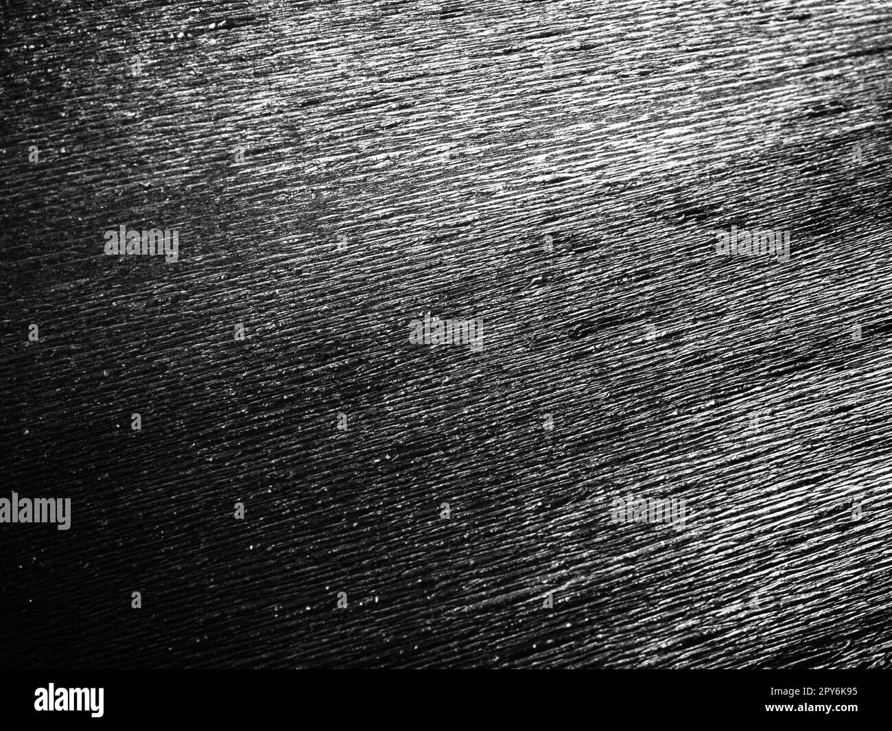 Schwarzes oder graues Wellpapier. Unebene Oberfläche. Abstrakter einfarbiger Hintergrund. Gewellte Kanten des Papierbogens. Lichtverlauf. Gewellte Textur Stockfoto