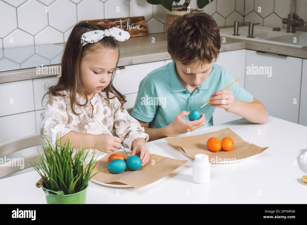 Porträt von zwei freudigen Kindern, Jungen und Mädchen, mit einem Pinsel, der Ostereier färbt. Familientradition Stockfoto