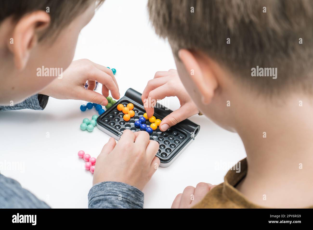 Jungs spielen Tische Tetris auf dem Tisch, aus der Nackenansicht. Die Hände der Spieler sammeln farbige Details auf dem Spielbrett. Brettspiele. Stockfoto