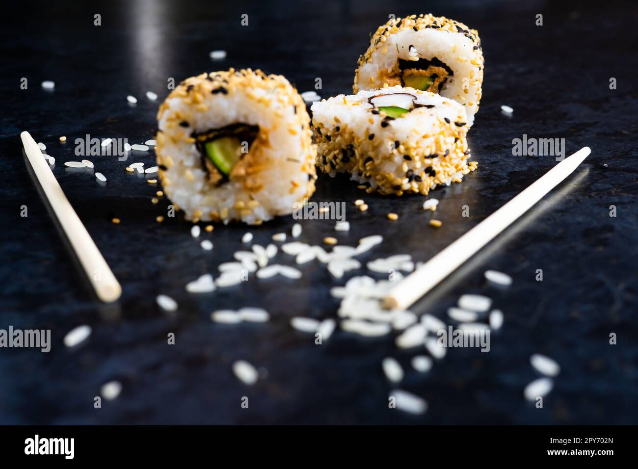 Sushi auf einer schwarzen Tischplatte mit Holzstäbchen. Japanisches Essen im Restaurant. Stockfoto
