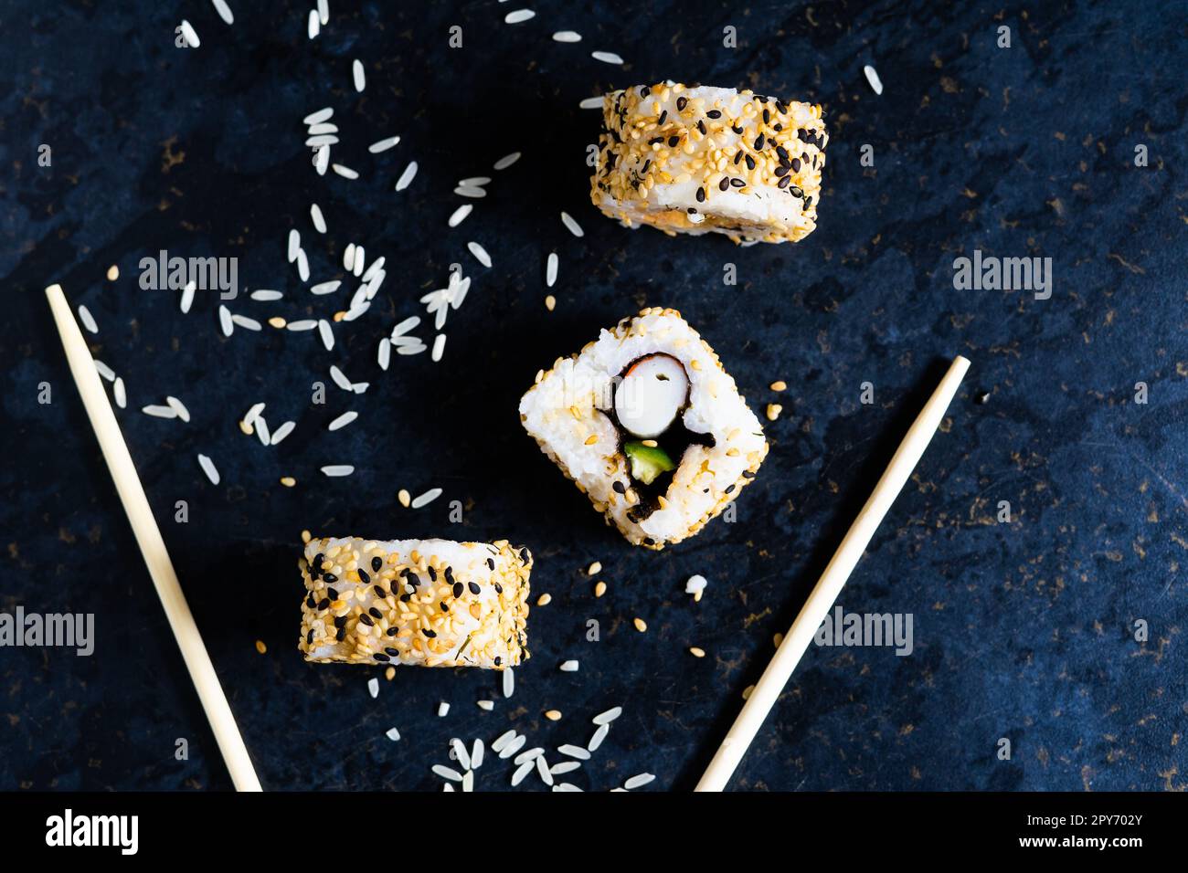 Sushi auf einer schwarzen Tischplatte mit Holzstäbchen. Japanisches Essen im Restaurant. Stockfoto