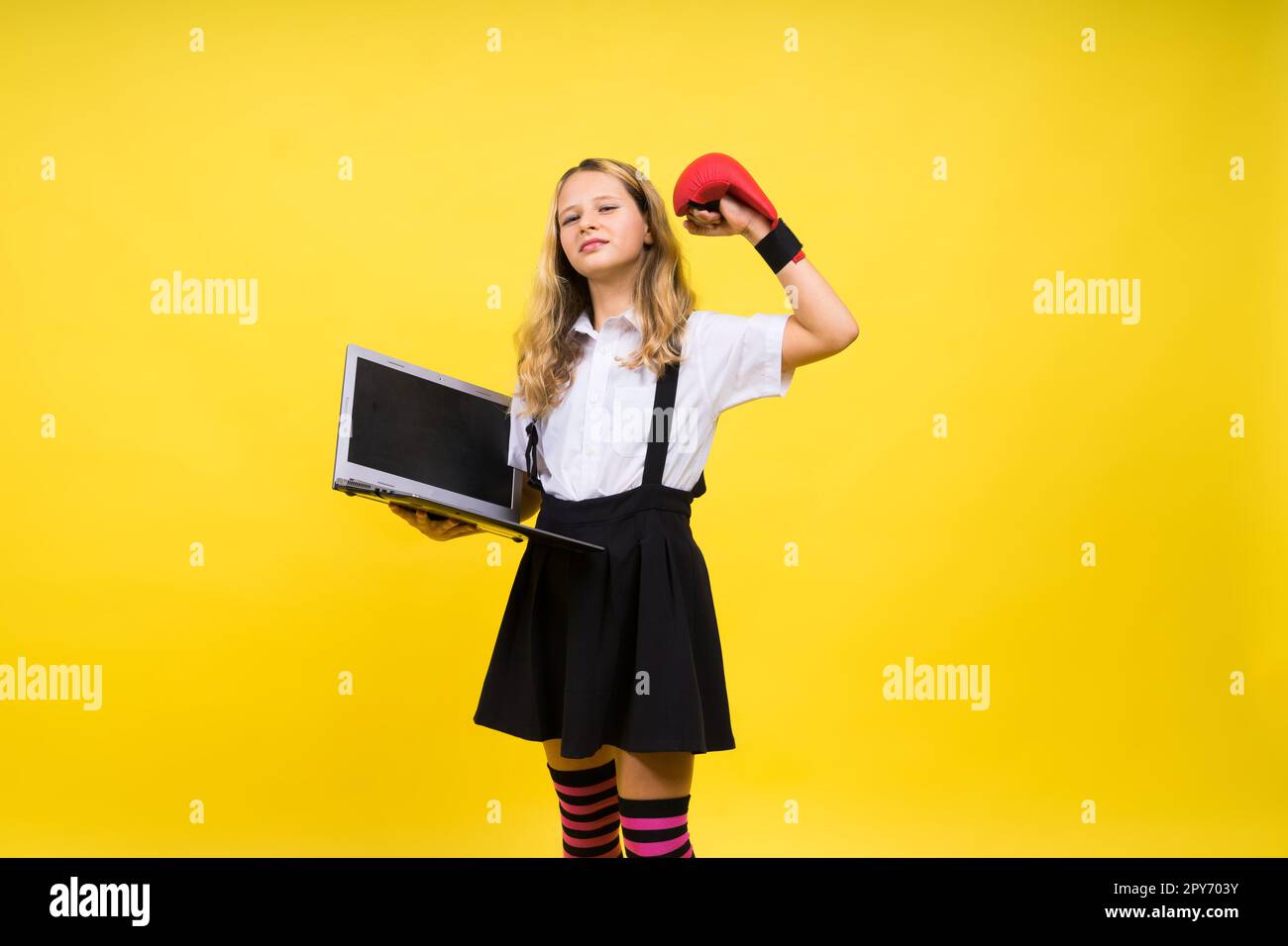 Ein kleines, glückliches, blondes Mädchen, das 12-13 Jahre alt ist, mit einem Laptop-pc. Kinderkinderkindliches Lifestyle-Konzept. Stockfoto