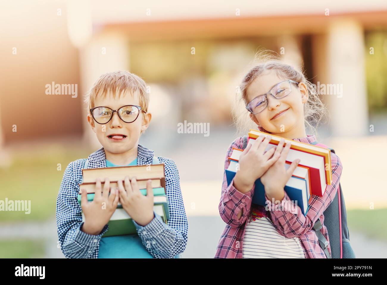 Mädchen und Junge in Brille stehen mit Büchern in den Händen. Stockfoto