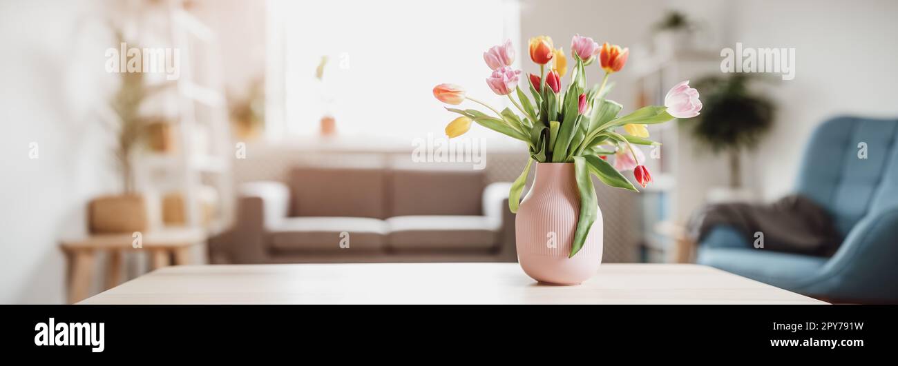 Ein Haufen Tulpen in rosa Vase, die drinnen auf dem Holztisch stehen. Stockfoto