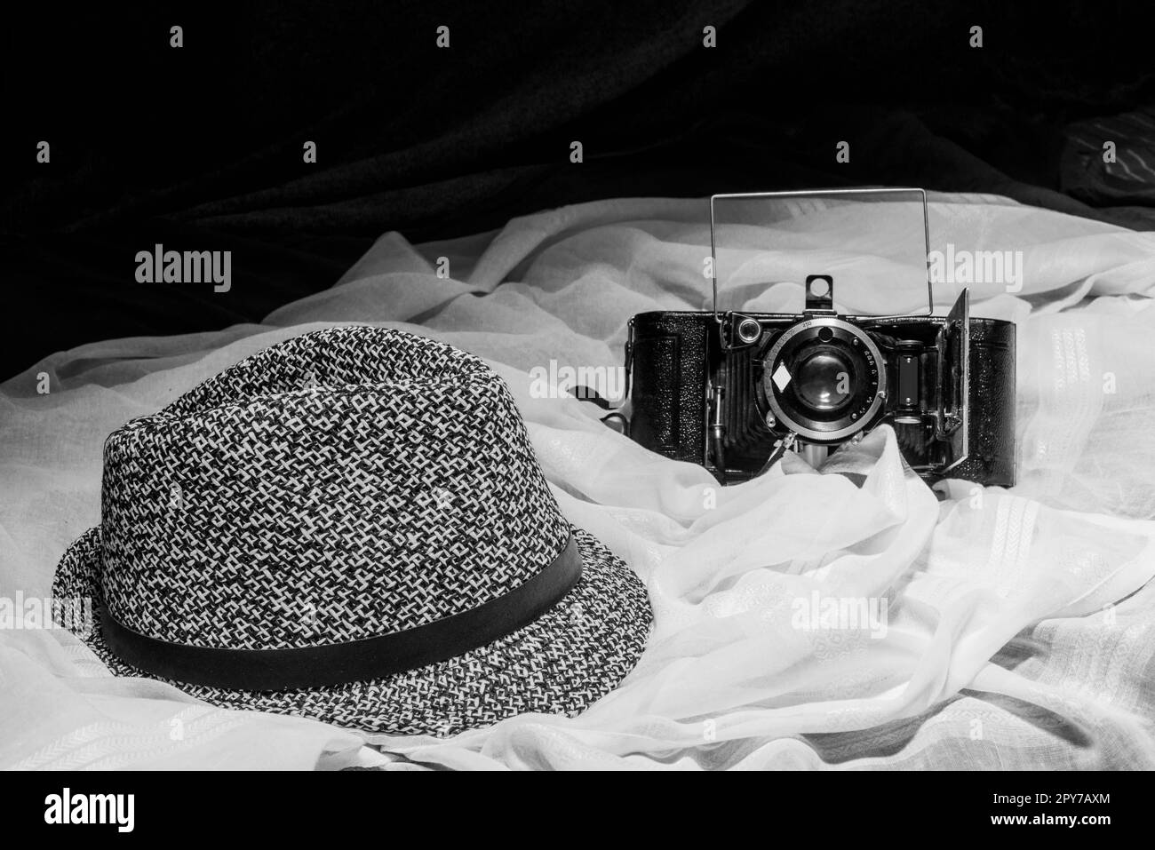 Ein schlichtes Schwarz-Weiß-Stilleben mit einer jeans-Mütze und einer klassischen Fotokamera Stockfoto