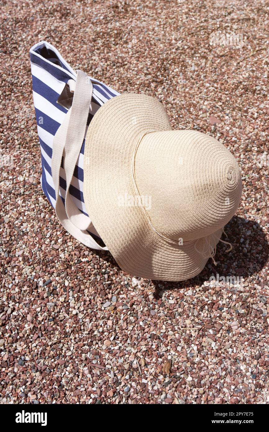 Strandzubehör Tasche und Sonnenhut auf Kieselstrand in der Nähe des Meeres. Sommerhintergrund. Stockfoto