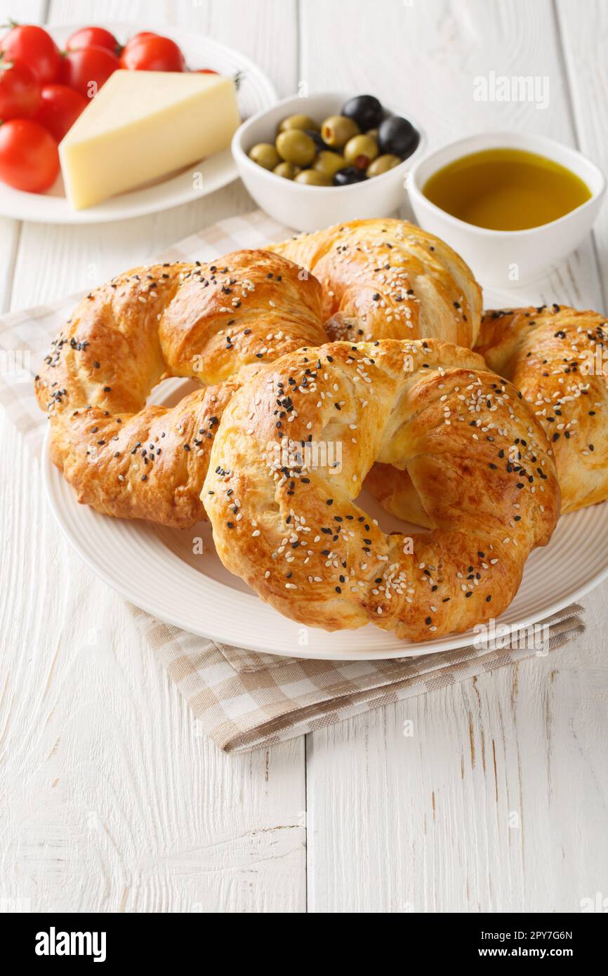 ACMA Soft Bagels im türkischen Stil serviert mit Tomaten, Käse, Oliven und Olivenöl auf dem Teller auf dem Tisch. Vertikal Stockfoto