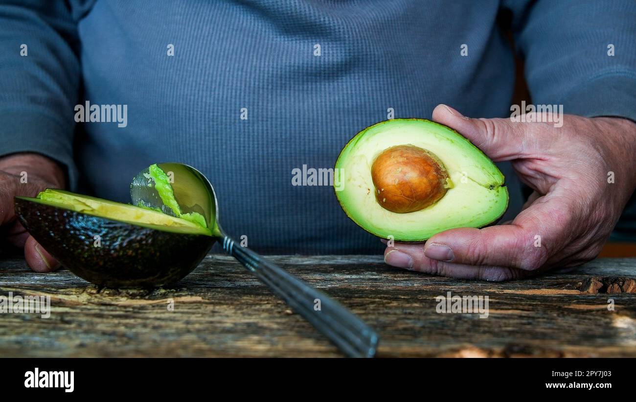 Mann mit Avocado auf einem rustikalen Holztisch Stockfoto