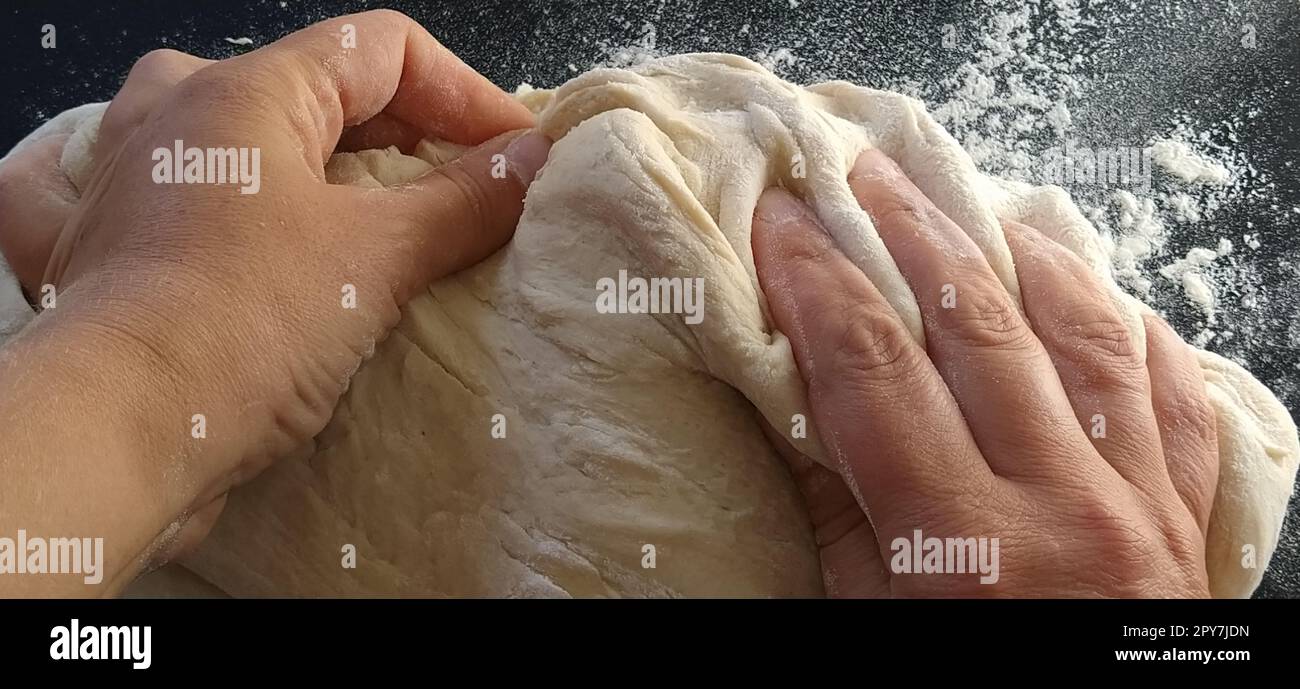 Die Hände kneten den Teig. Die Frau knete Teig zum Backen oder Knödel. Herstellung von Mehl, Wasser und Eimasse für die thermische Verarbeitung. Koch-Hände Stockfoto
